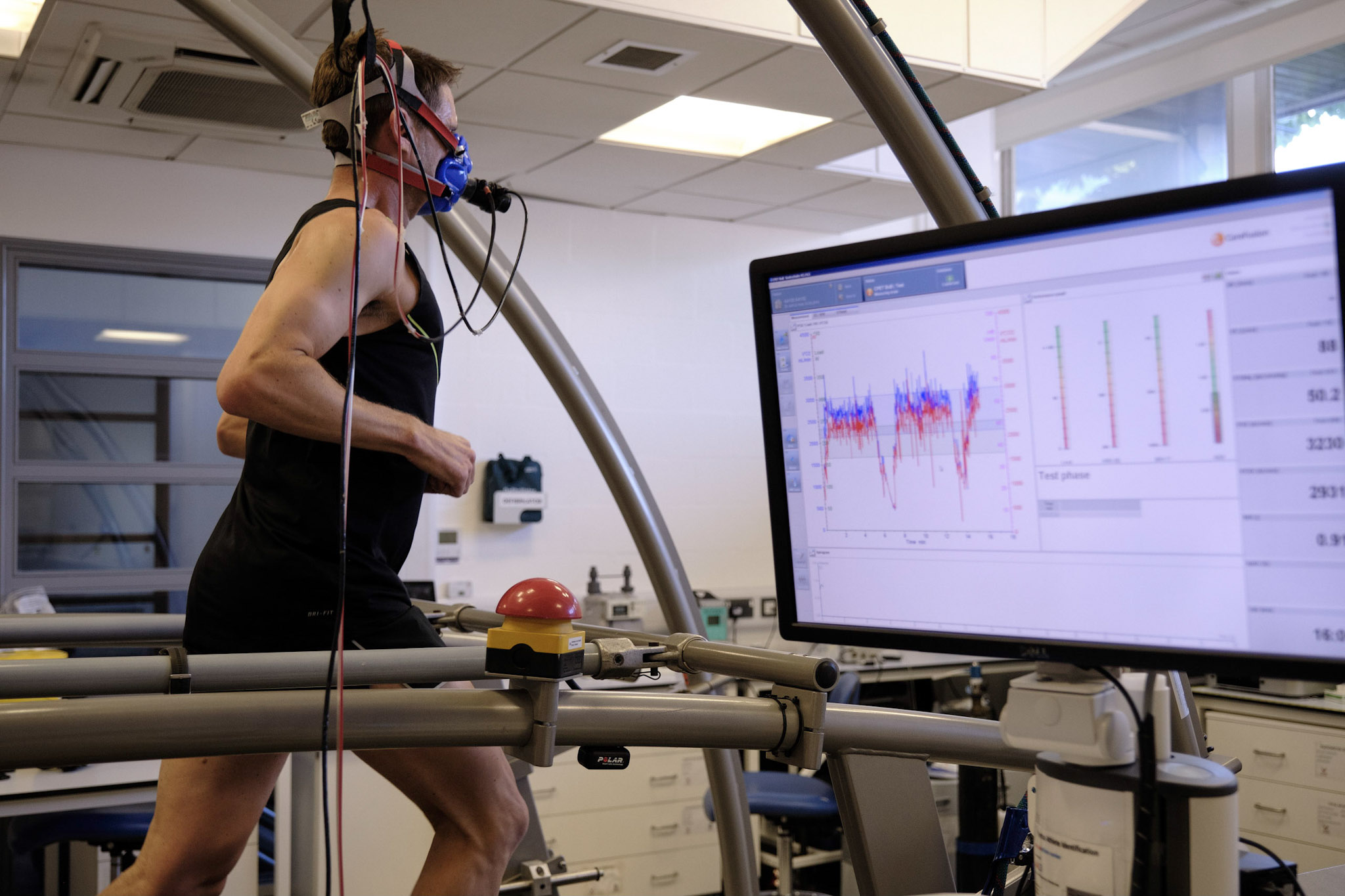 an athlete in a fitness testing lab with a mask over his nose and mouth a computer screen is in the foreground